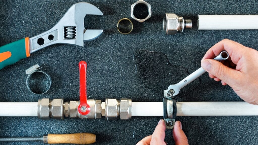 Plumber repairing a pipe valve with an adjustable wrench in Fleming Island