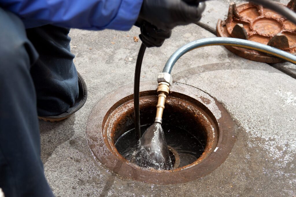 Plumber hydro jetting a sewer line through a manhole in Fleming Island