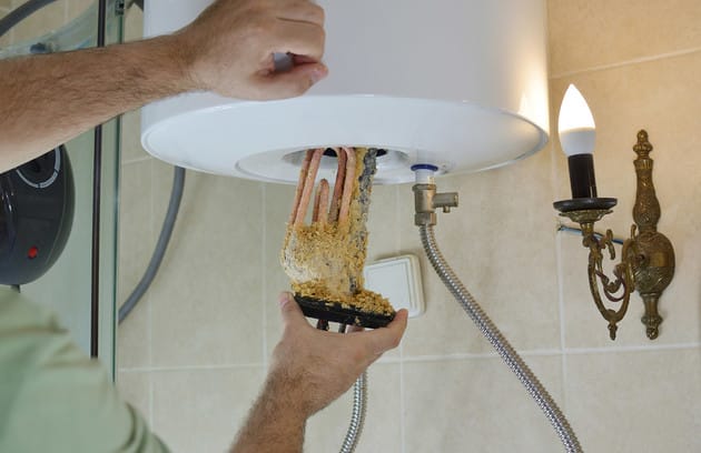 Technician removing mineral buildup from a water heater in Fleming Island